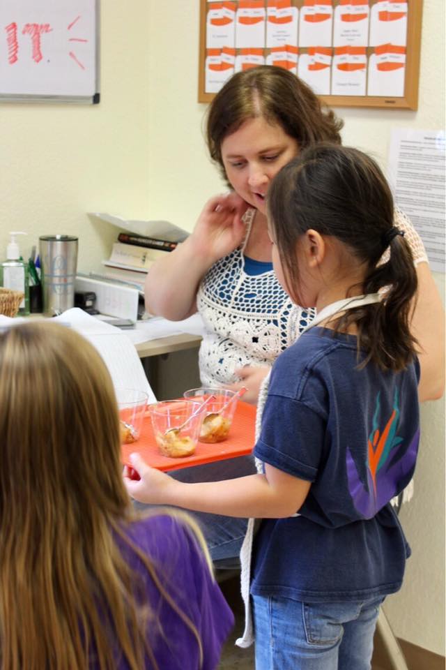 Student shows teacher her work displayed on a tray